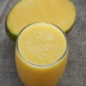 simple orange color smoothie cup with a mango behind it