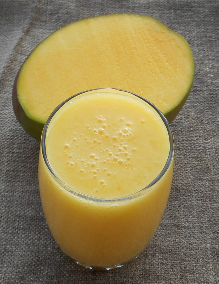 simple orange color smoothie cup with a mango behind it