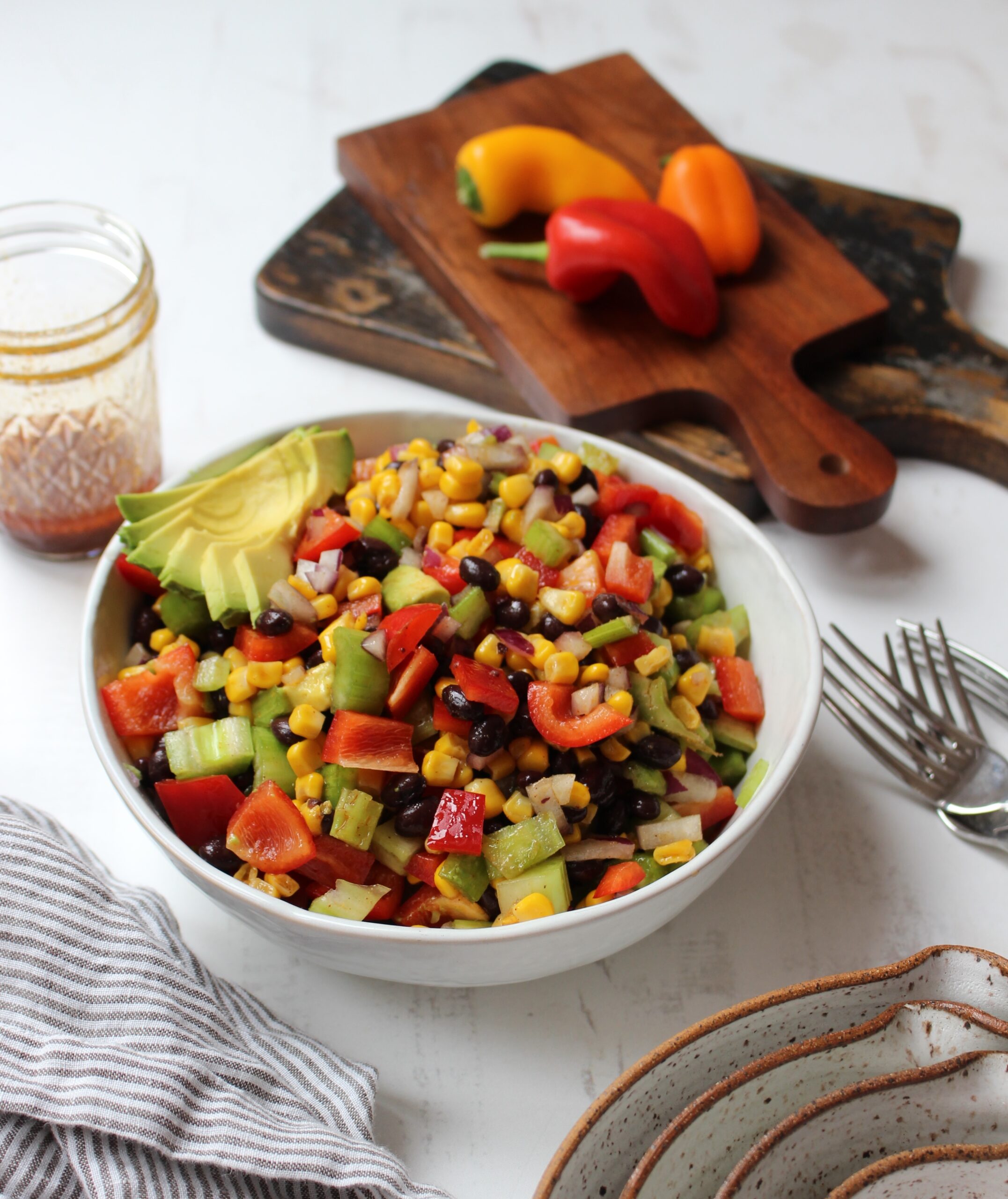 mexican salad in a bowl with vinaigrette on the left and fork on the right