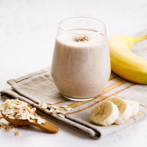 White smoothie with banana slices and oats on the side