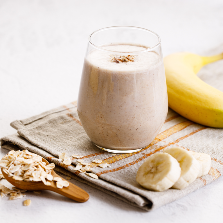 White smoothie with banana slices and oats on the side