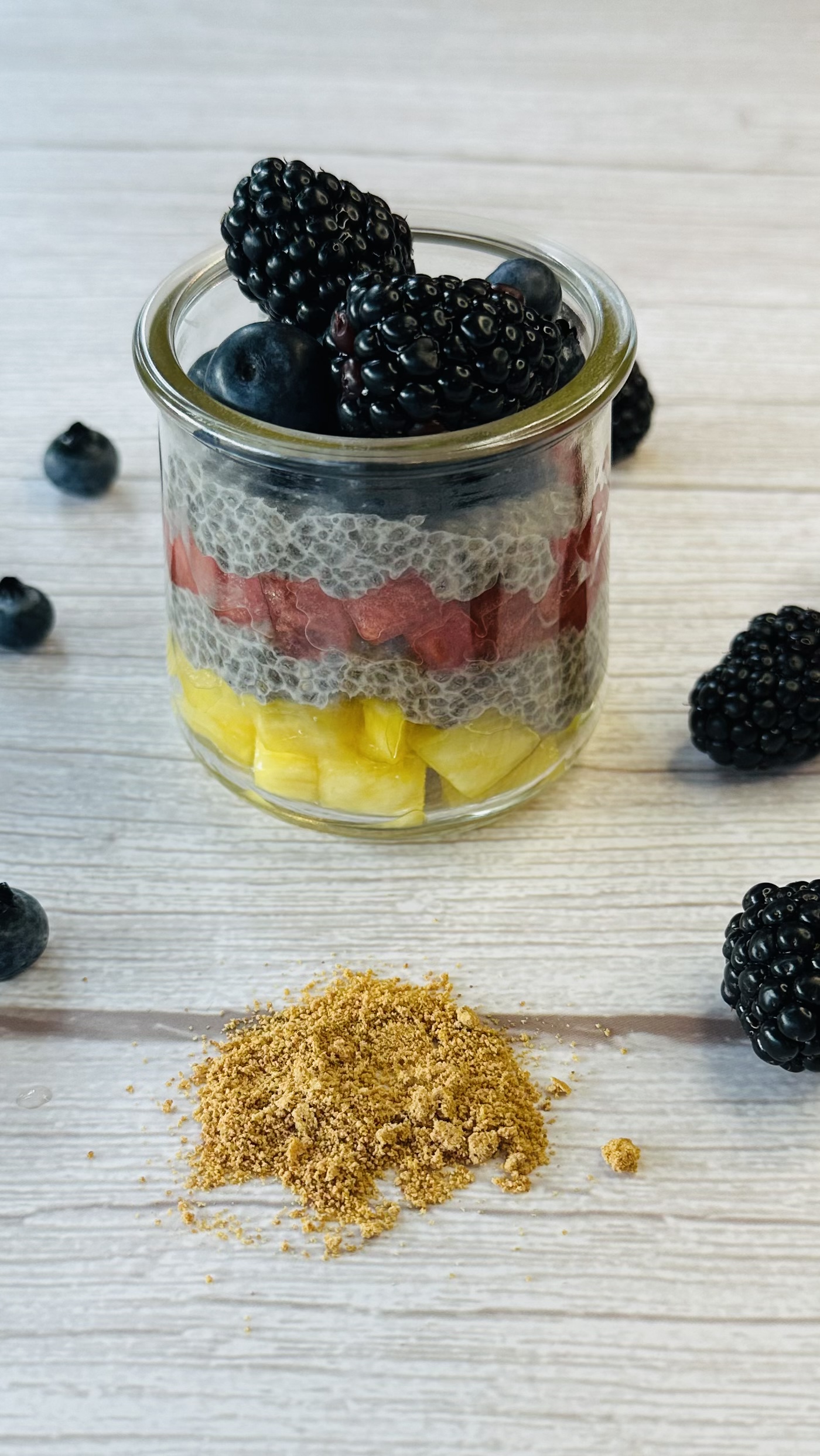 little jar with chia pudding in layers with pineapple chunks, watermelon and berries