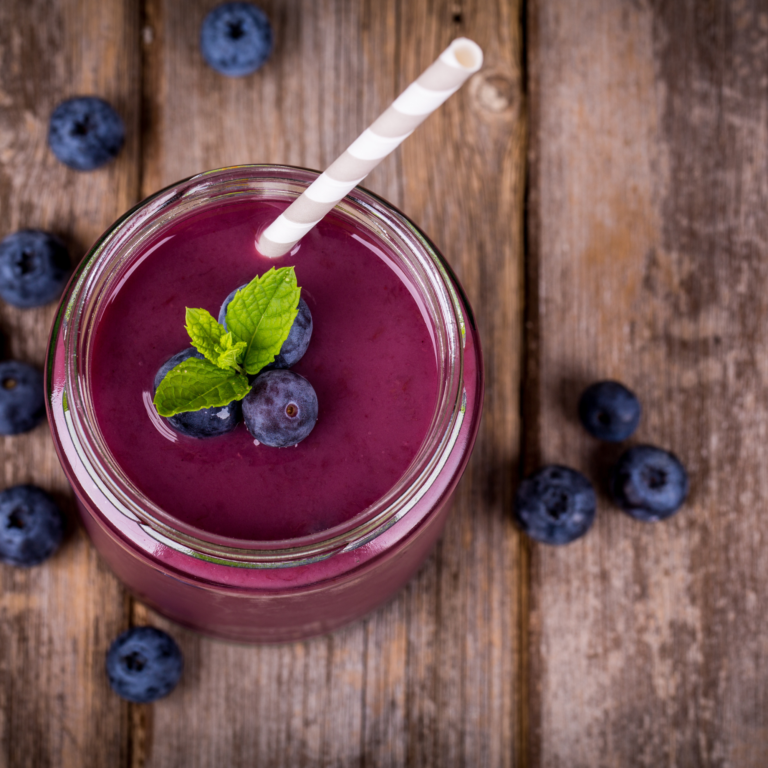 blueberry smoothie with a straw in it and blueberries around it