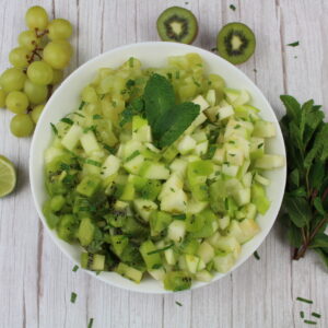 bowl of green fruit salad from the top with mint on the side