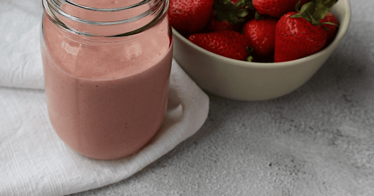 vegan strawberry milkshake with bowl of strawberries