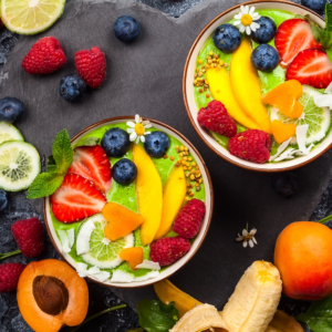 very pretty smoothie bowl with lots of fruits arounf it