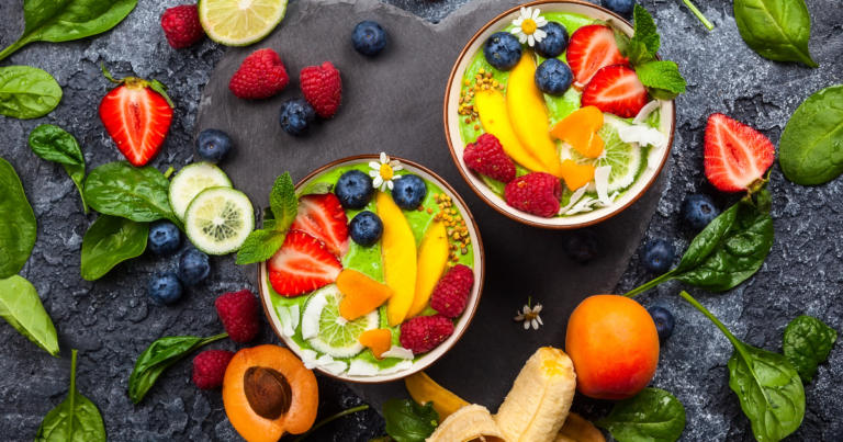 very pretty smoothie bowl with lots of fruits arounf it